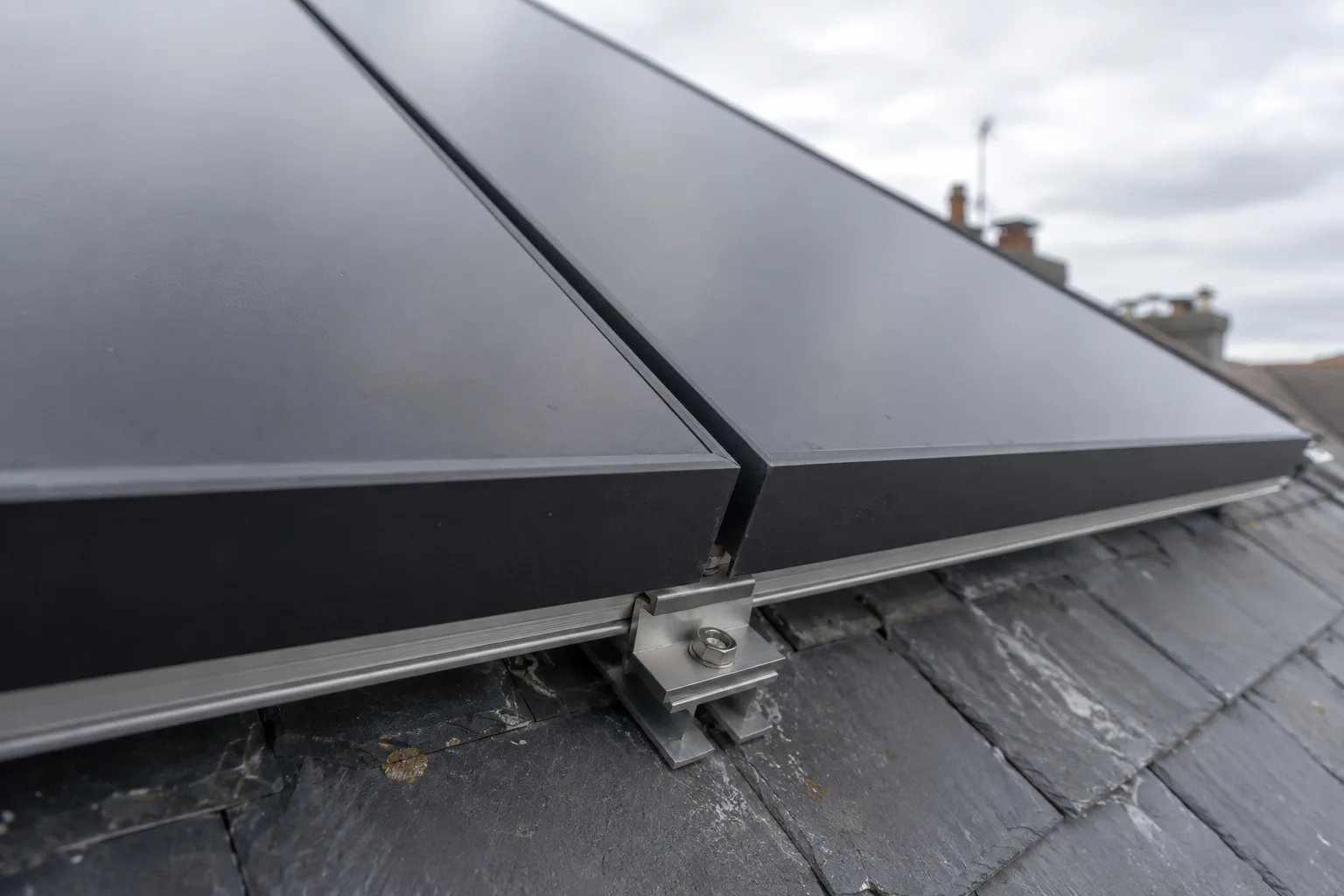 Power your UK home with AIKO Close view of two solar module frames meeting on a mounting rail with the clamp between them